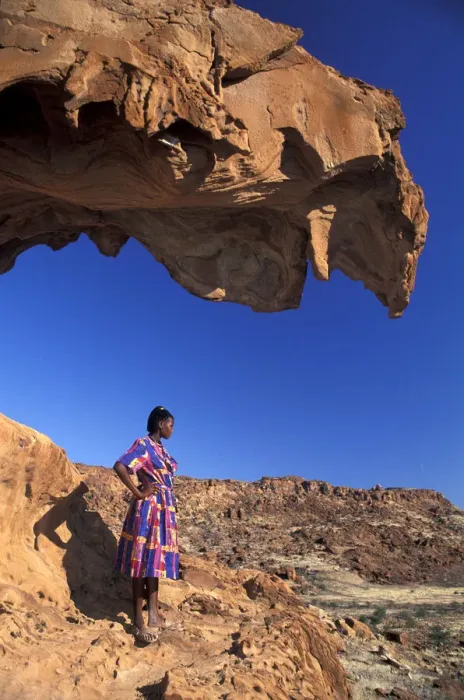 Framed Print : Namibia. African Woman standing under Red Rock formations, Twyfelfontein, Namibia, Africa Framed Print : Namibia. African Woman standing under Red Rock formations, Twyfelfontein, Namibia, Africa